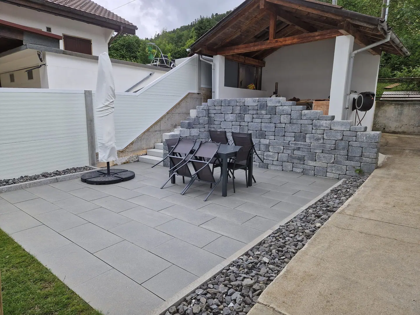 Terrasse en dalles de granit bordée d'un mur en blocs de pierre et d'un escalier extérieur